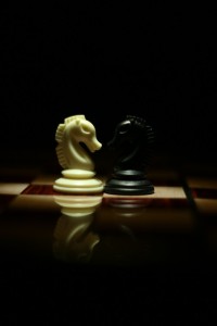 two-white-and-black-chess-knights-facing-each-other-on-chess-board