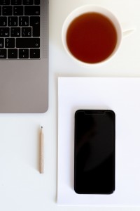 cup-of-tea-near-laptop-keyboard-with-smartphone-on-paper-and-3975571